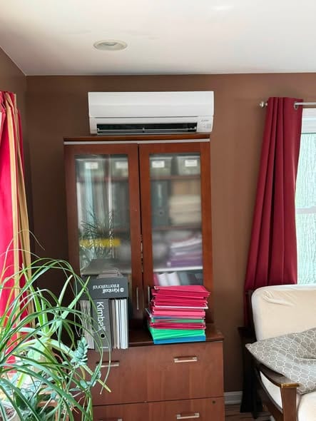 Ductless wall unit mounted above a cabinet in a living room