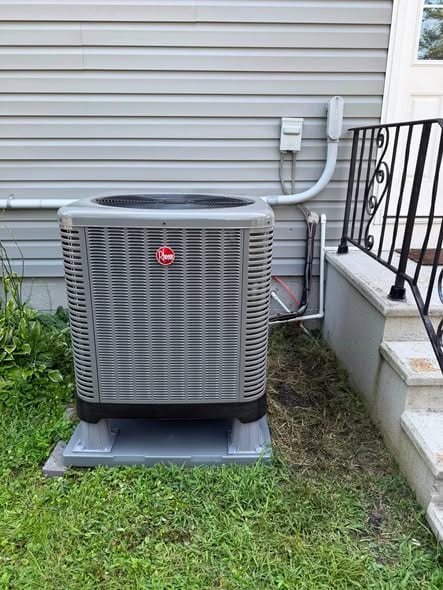 Outdoor unit on a pad beside front steps and a railing