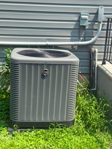 Close view of a new outdoor condenser set in the grass beside a home