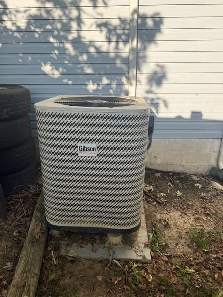 Outdoor condenser set level on blocks beside blue siding