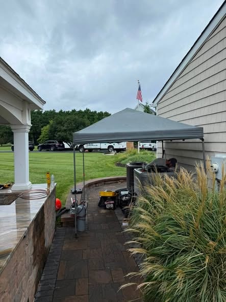 Outdoor job site with a canopy tent, equipment and a paved patio