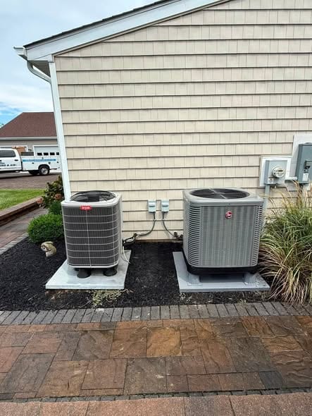 Two new outdoor units on a pad with the Hamilton truck parked in the background