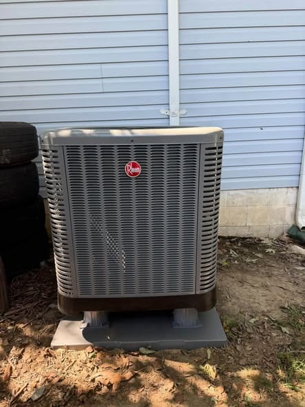 Outdoor condenser on a fresh pad against blue siding