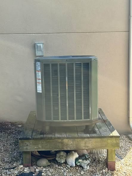 Outdoor unit on a raised wood stand over a gravel bed