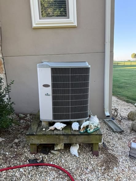 Outdoor unit on a raised wood platform with open fields behind the house