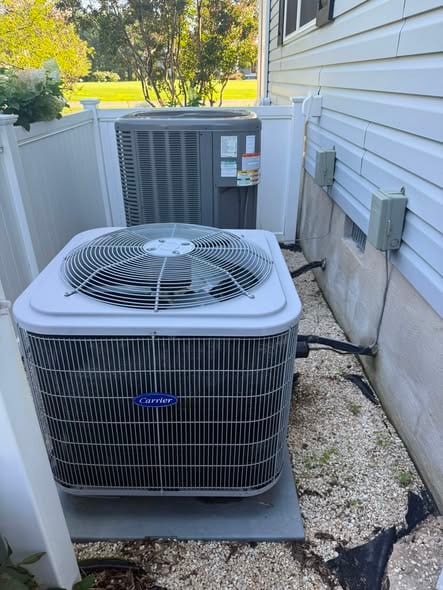 Outdoor units set behind a white vinyl fence beside a sided home